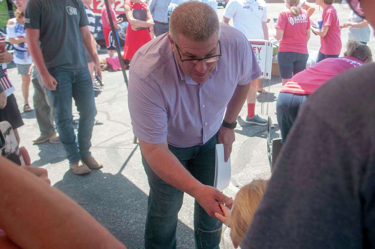 Darren Bailey, a Republican candidate seeking nomination to run against incumbent Gov. J.B. Pritzker, shakes the hand of 5-year-old Eleanor Walker in Jacksonville. Bailey was on a bus tour Tuesday and spoke with voters about why he should be nominated and elected governor. 