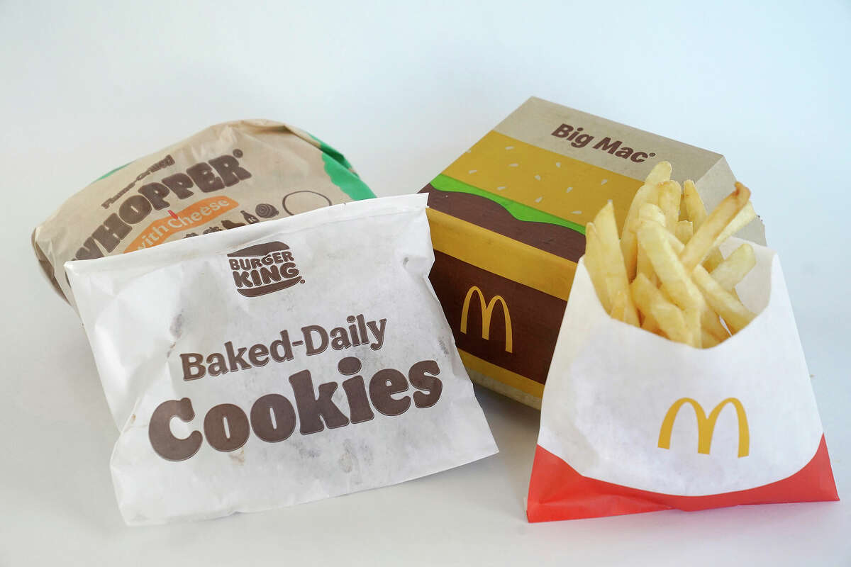 A Burger King Whopper in a wrapper (back left) and a bag of Burger King cookies (from left) rest next to a McDonald's Big Mac in a container and a bag of McDonald's fries. Environmental and health groups are pushing dozens of fast food companies, supermarkets chains and other retail outlets to remove PFAS from their packaging.