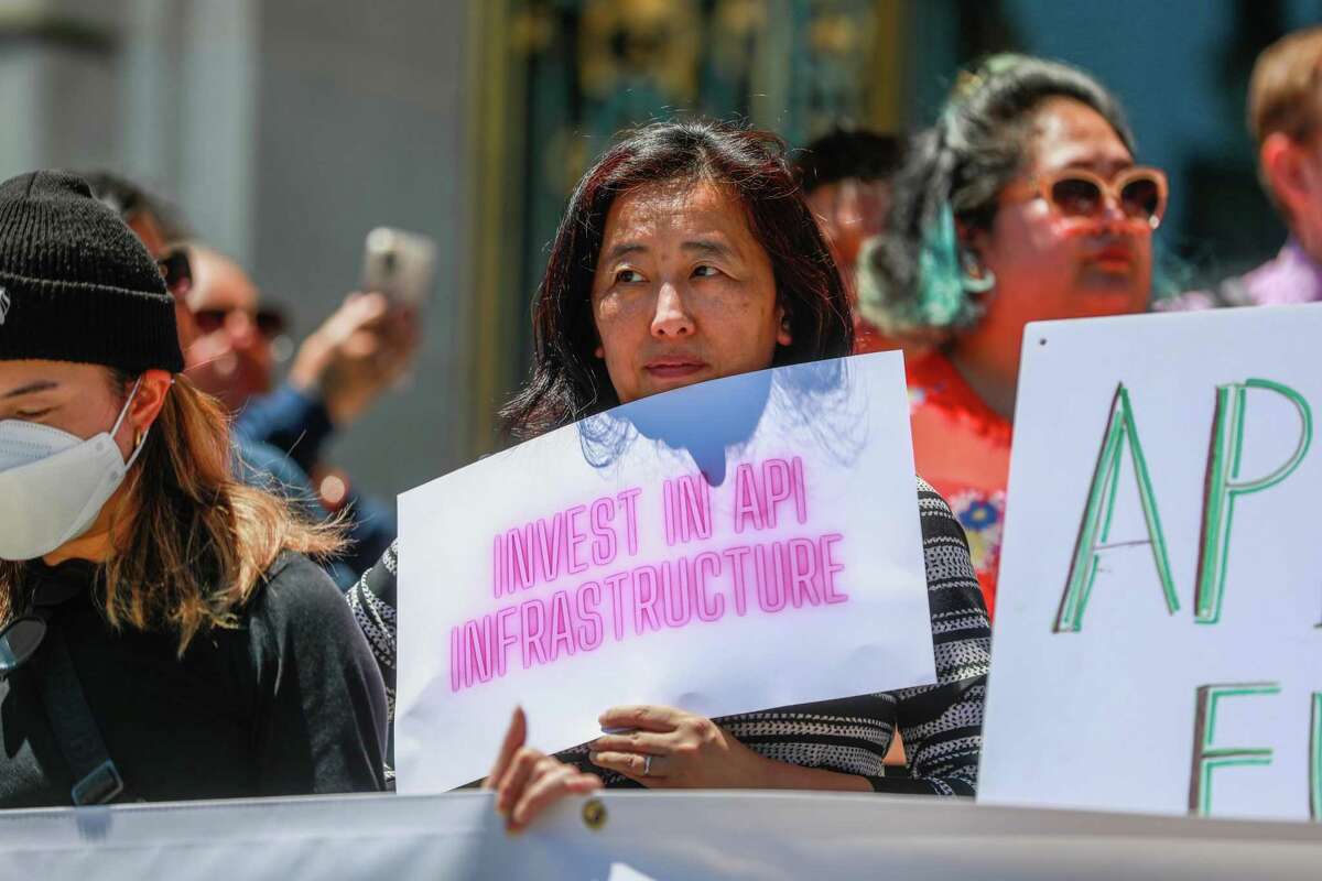 Abby Chen holds up a poster supporting legislation to invest millions of dollars in San Francisco’s Asian and Pacific Islander communities over the next two years outside City Hall on Tuesday, June 14, 2022.