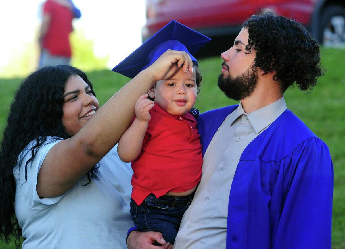 Henry Abbott Technical High School graduate Jacob Fast, right, watches as his cousin Massiel Medina puts his graduation on her son Jair Charon's head as they pose for photos at the conclusion of the school's Class of 2022 Commencement held at WCSU’s O'Neill Center in Danbury, Conn., on Tuesday June 14, 2022.