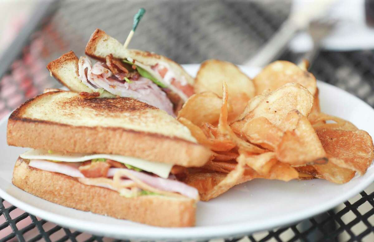 An club sandwich with deli ham & turkey, lettuce, tomatoes, Swiss cheese, garlic aioli on a toasted brioche is seen alongside house-made chip at Hunger Crush Cafe, Tuesday, June 14, 2022, in Montgomery.