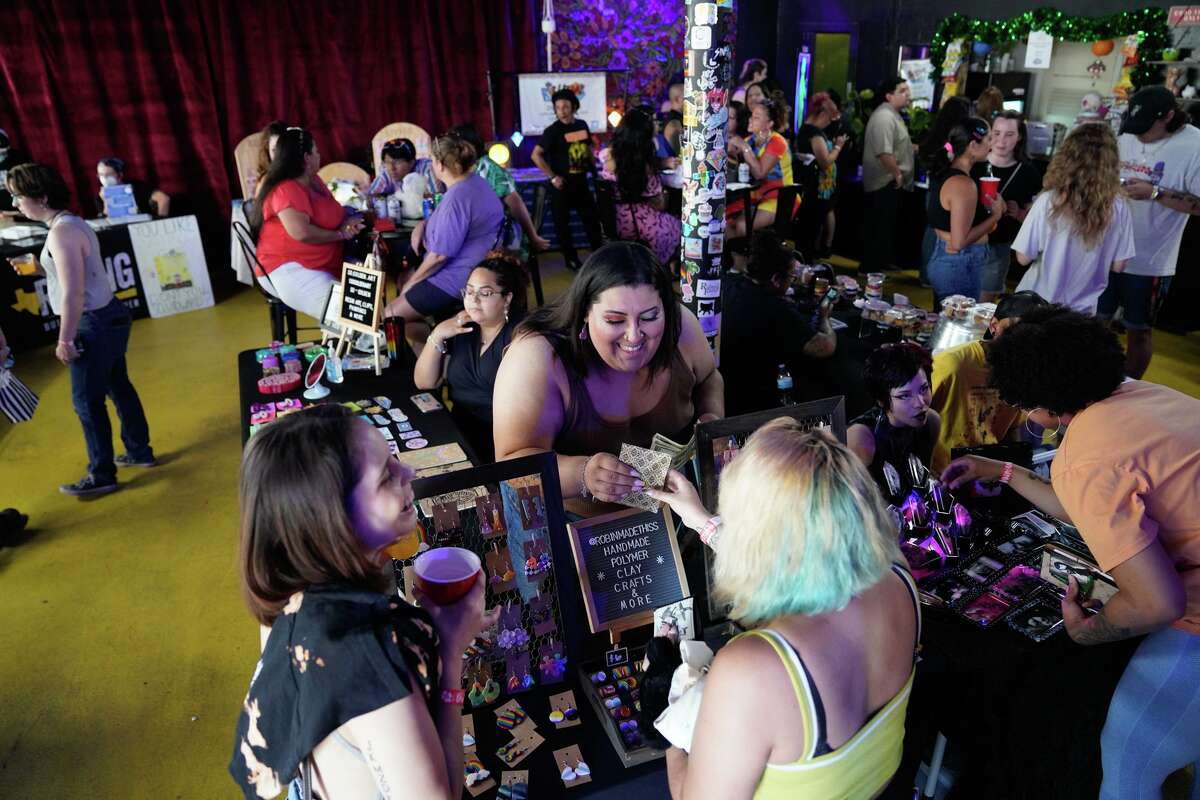 Robin Rollins works with customers at her table during the Sunday afternoon performances and market at The Starlighter event venue in the Deco District.