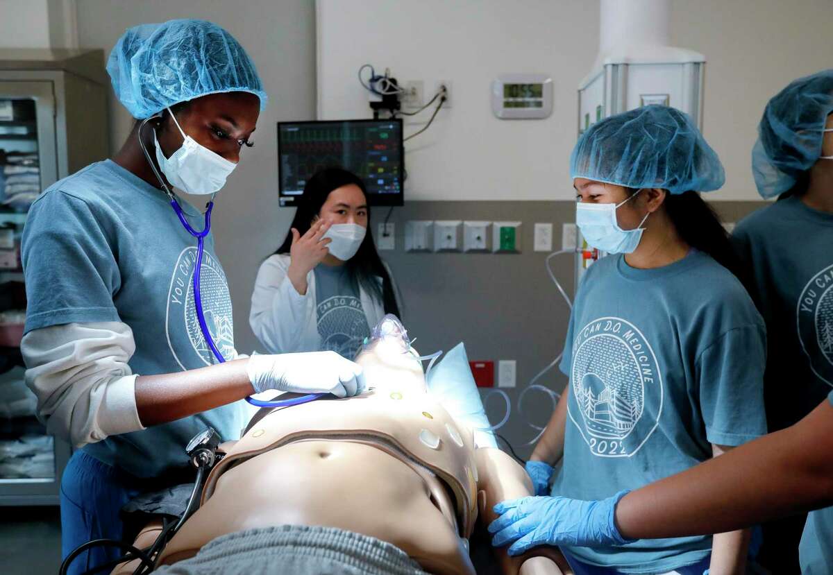Conroe High School students Shanaria Price, left, and Mykah Santiago, are walks through the thinking in a medical situation by medical student Kim Chi Dang, center, as part of a four-day summer camp at Sam Houston State University’s College of Osteopathic Medicine, Wednesday, June 15, 2022, in Conroe. The free camp featured several sessions including a mock emergency situation, physical examinations and a health care professional job fair.