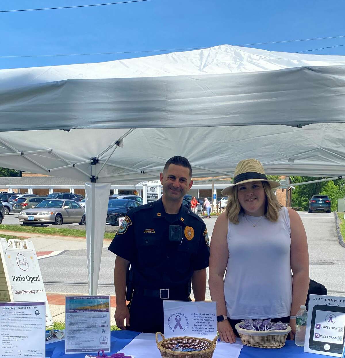Wilton Police Department Captain Robert Cipolla, left, and Associate Director of the Domestic Violence Crisis Center Ann Rodwell-Lawton, right, promote awareness of their partnership to combat domestic violence within the community at the Wilton Farmer's Market.