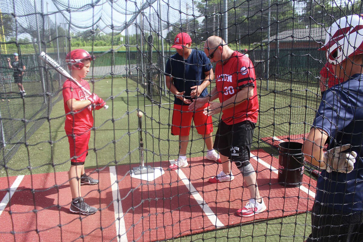 Camper Zachary Thornton, right receives instruction from a coach Jimmy McGibany during a session in the batting cages at Alton School during Redbirds Baseball Camp at Alton High School on Wednesday.