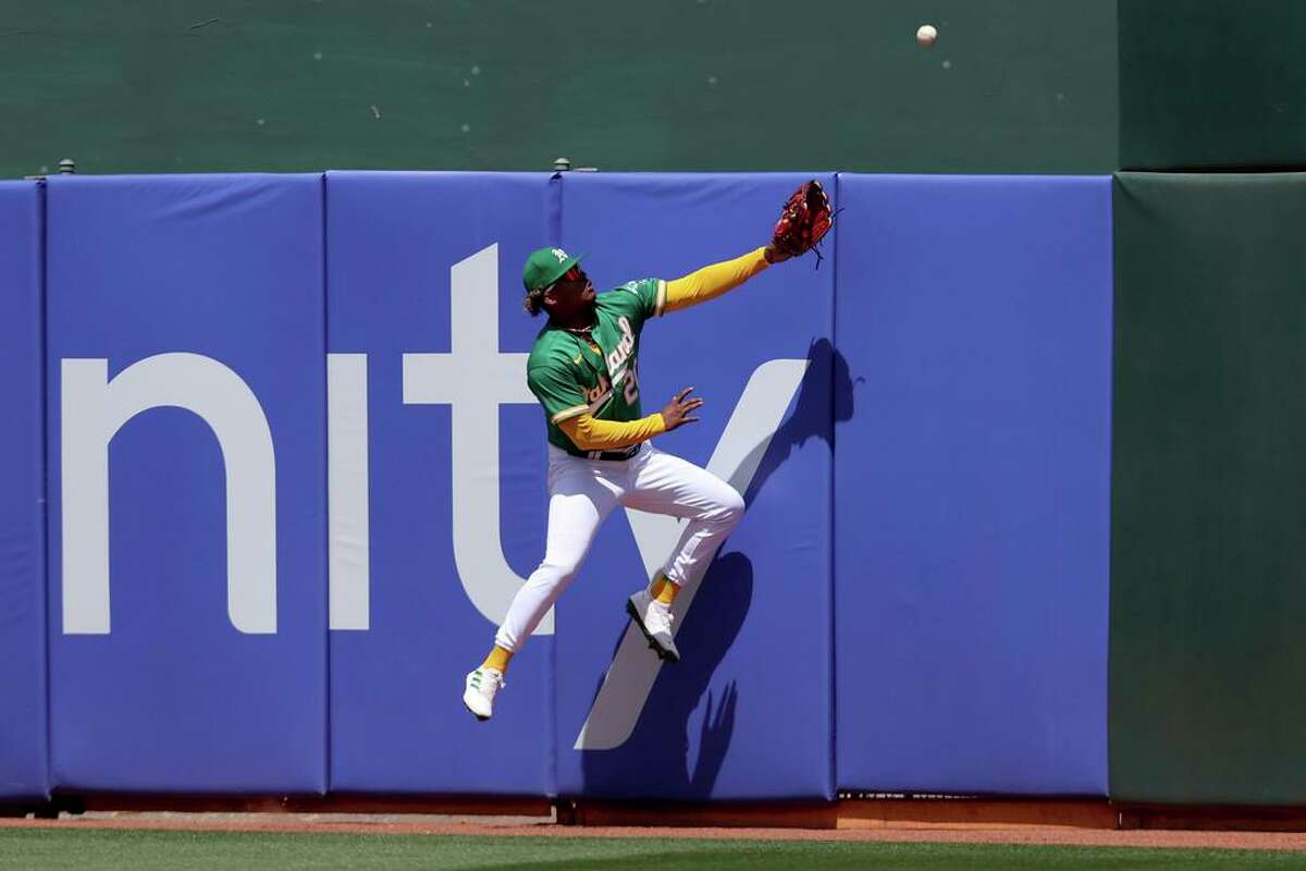 Oakland Athletics center fielder Cristian Pache leaps unsuccessfully for a grand slam hit by Texas Rangers' Marcus Semien during the fifth inning of a baseball game in Oakland, Calif., Saturday, May 28, 2022. (AP Photo/Jed Jacobsohn)