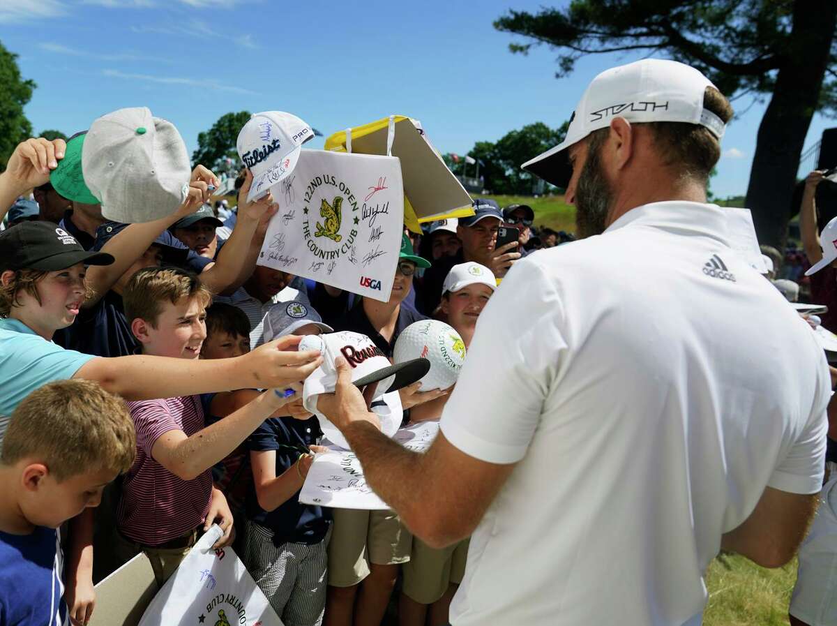 Dustin Johnson, one of the leading players to join the Saudi Arabian-backed LIV tour, signs autographs after a practice round for the U.S. Open at The Country Club in Brookline, Mass.