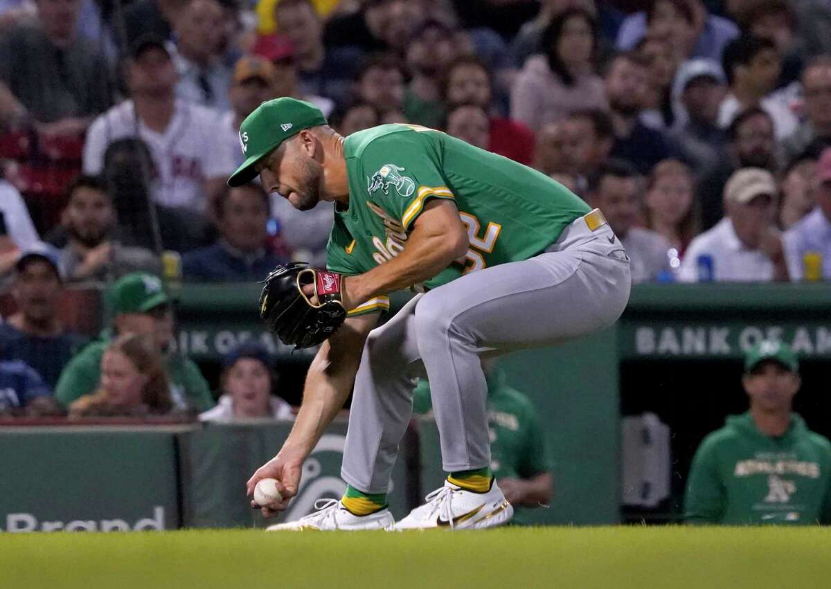Oakland Athletics starting pitcher James Kaprielian bare-hands the ball throwing to first on a single by Boston Red Sox's Trevor Story during the fourth inning of a baseball game at Fenway Park, Wednesday, June 15, 2022, in Boston. Kaprielian was charged with a throwing error on the play. (AP Photo/Mary Schwalm)