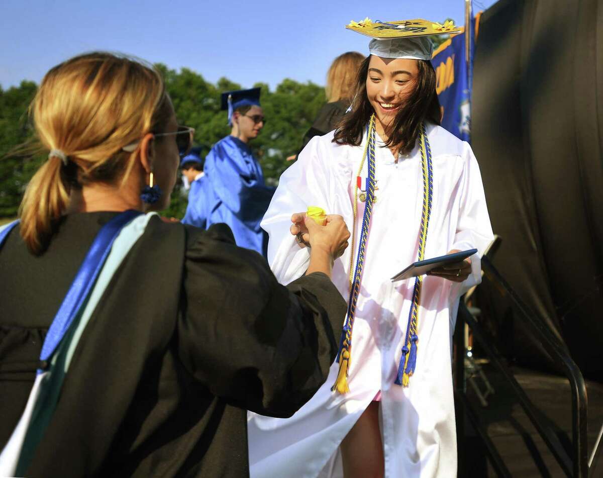 Graduate Norah Kolb is handed a cupcake after receiving her diploma at the Newtown High School Graduation in Newtown, Conn. on Wednesday, June 15, 2022.