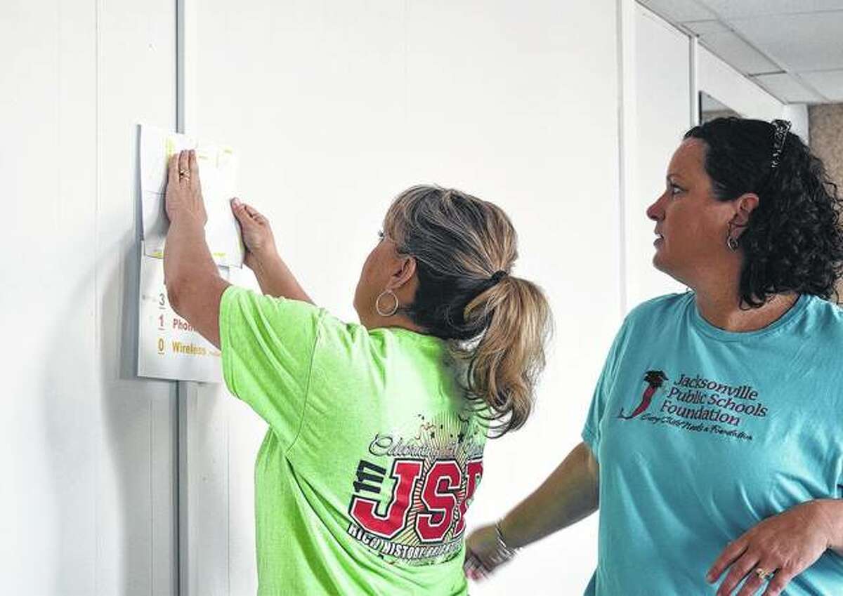Lori Karr (left) and Amy Albers put up a planner in 2018 in the new offices for Jacksonville School District 117. Albers will be leaving her position as executive director of the Jacksonville Public Schools Foundation in August after 12 years.
