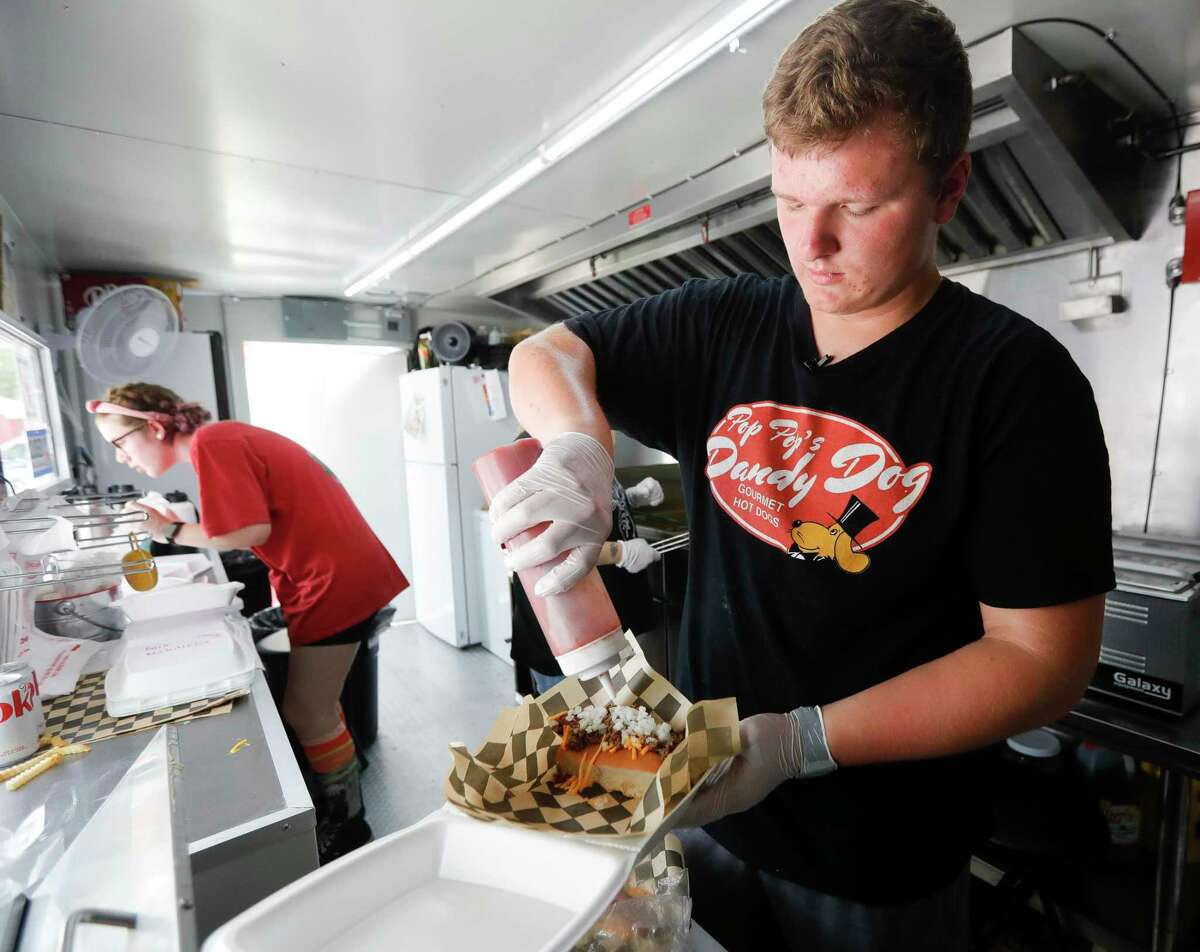 Jacob Irding assembles a hot dog for a customer at his food truck, Pop Pop’s Dandy Dogs, Tuesday, June, 14, 2022, in Montgomery. The 16-year-old Lake Creek High School student opened the truck on June 11 in downtown Montgomery.