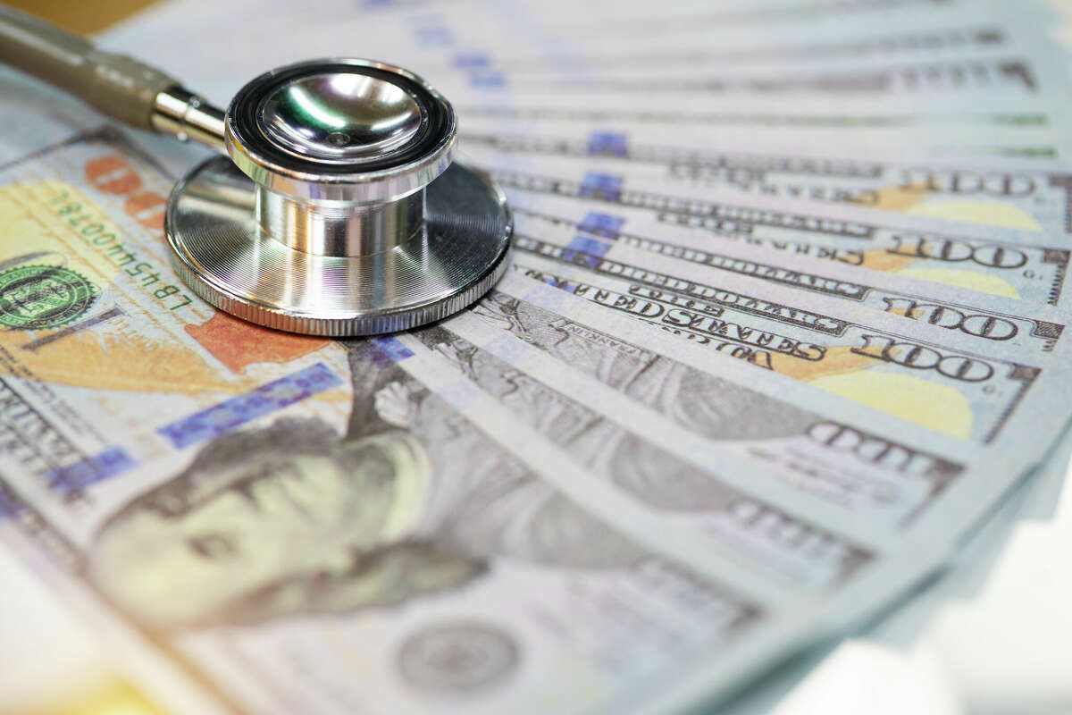 A stethoscope and money are pictured together in this stock photo.