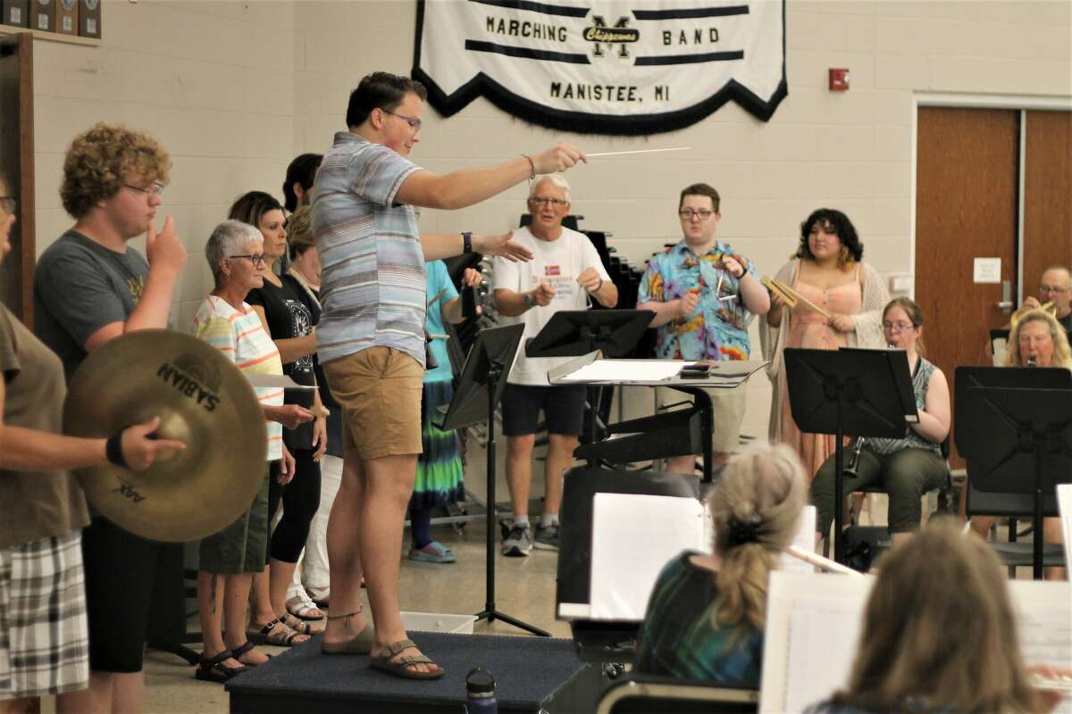 Conductor Ryan Biller leads the Manistee Community Band and Chamber Choir Tuesday during a rehearsal in the Manistee Middle High School band room.