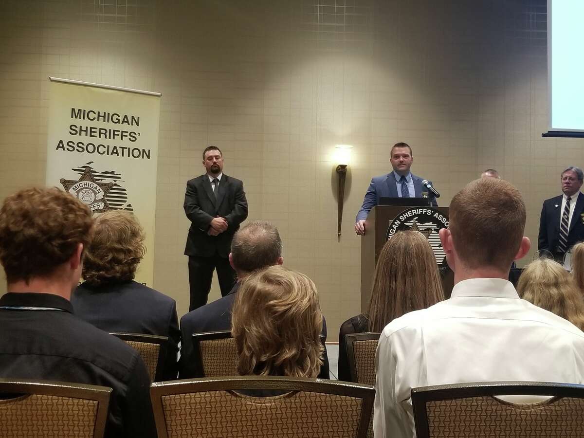 (From left) Brandon Gillispie stands as Brian Gutowski introduces Gillispie prior to him being awarded the Michigan Sheriffs’ Association Distinguished Service Medal.