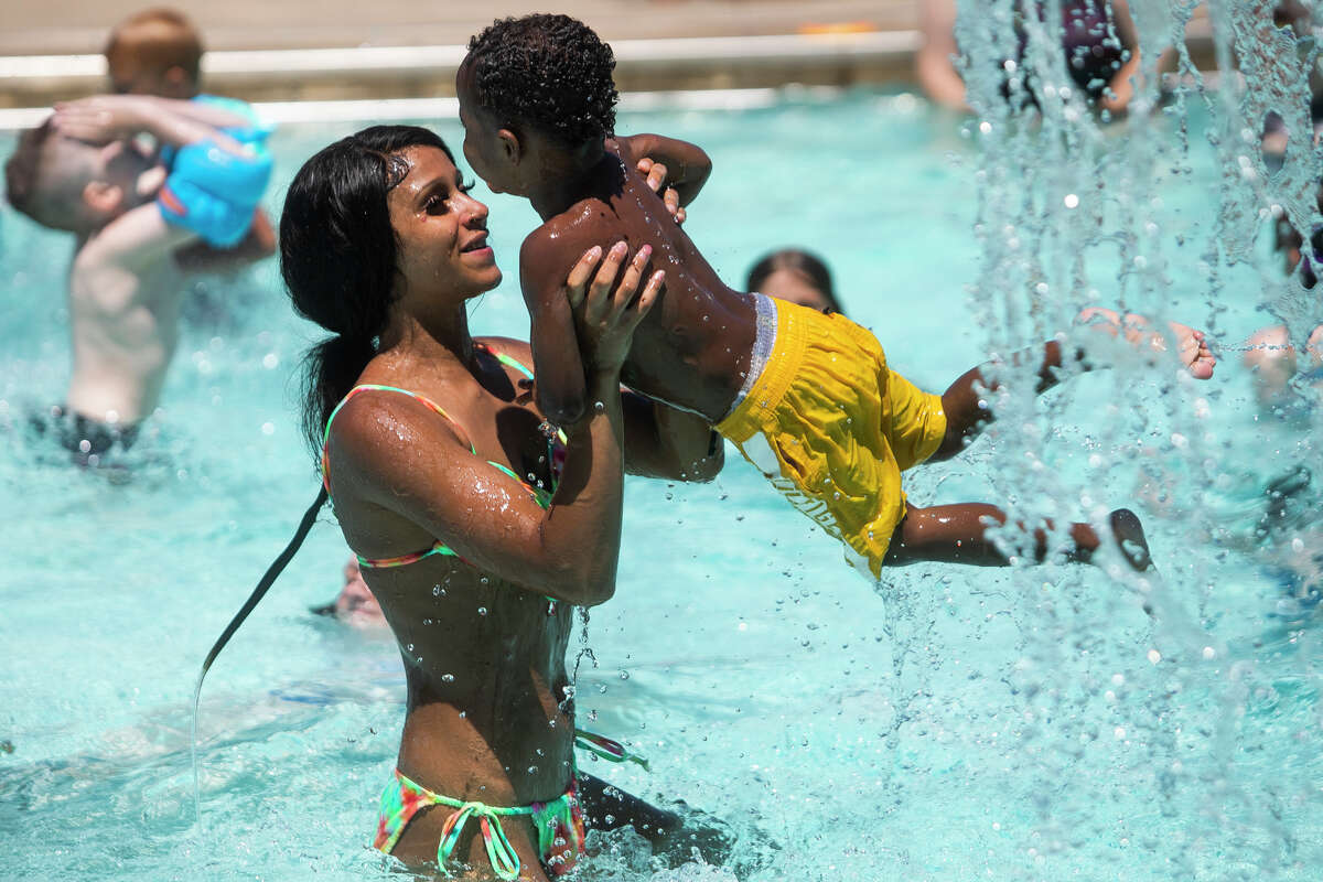 Alanna Legalley lifts her son, Da'Natus, 2, into the air as families cool off from temperatures in the high 80s at Plymouth Pool Thursday, June 16, 2022 in Midland.