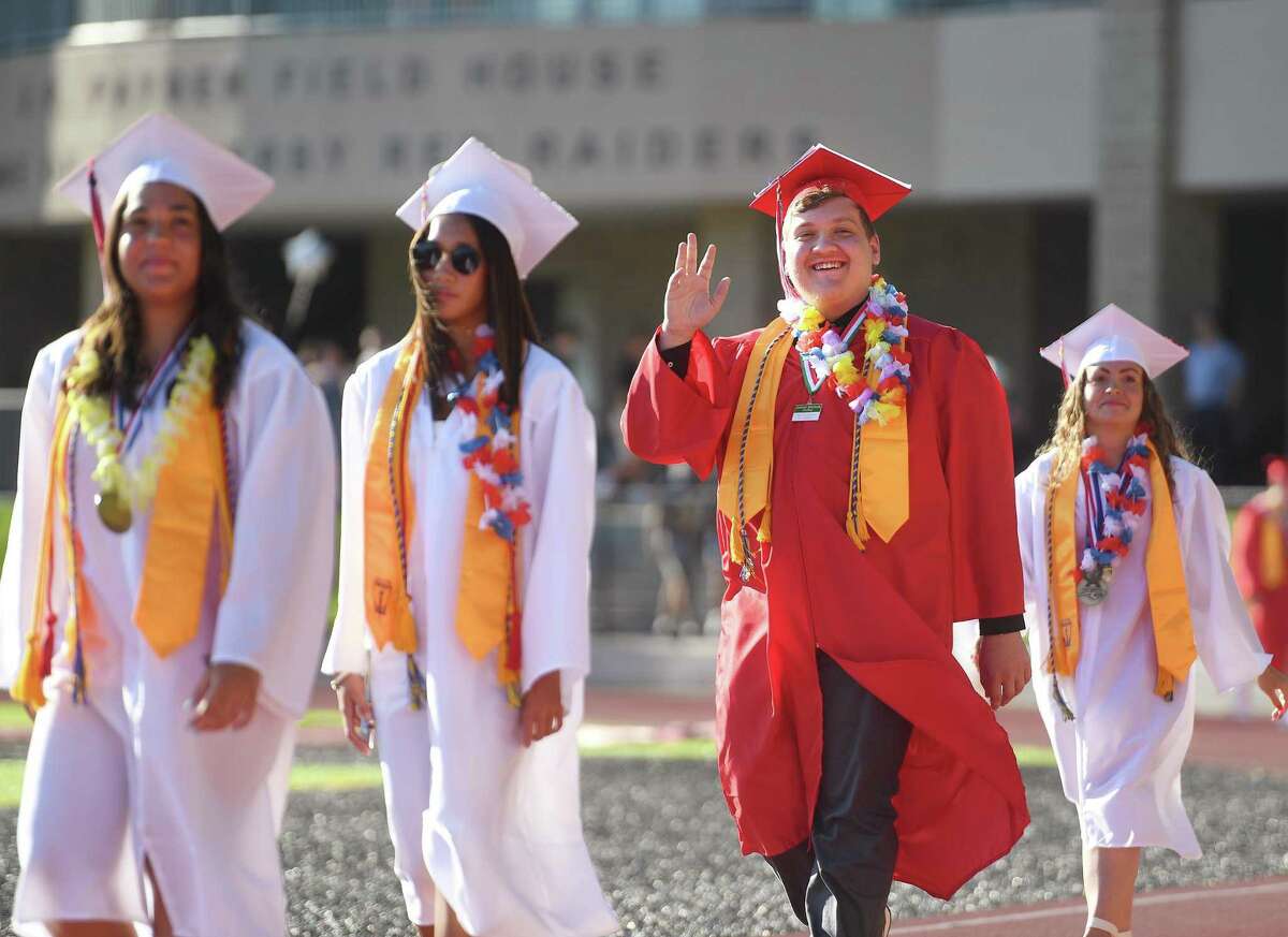 Graduate Shane Dedura waves to family in the stands as he walks in with his classmates to the Derby High School Graduation in Derby on Tuesday.