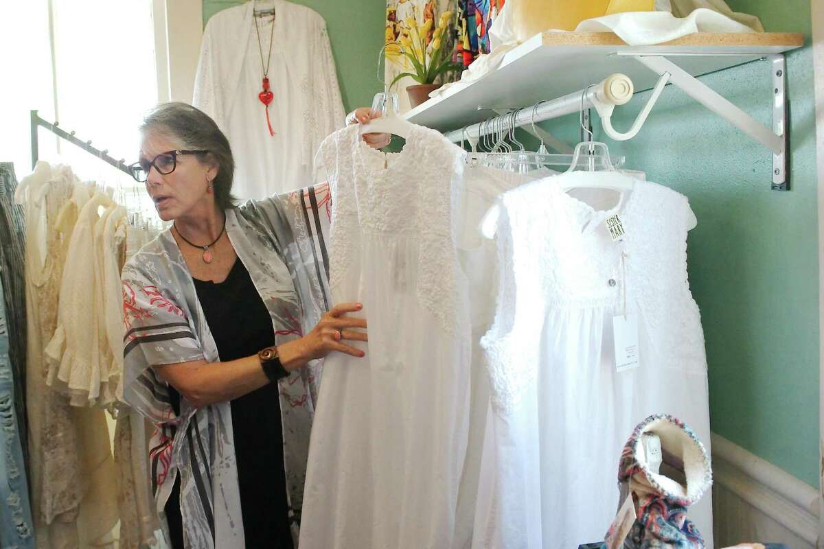 Kathy Madden, a sales associate at GingerSnaps boutique in League City, pulls items from the rack that would be appropriate attire at the League City White Linen Night Art Crawl and Auto Show, which is scheduled for Saturday, June 25 in the city’s historic district.