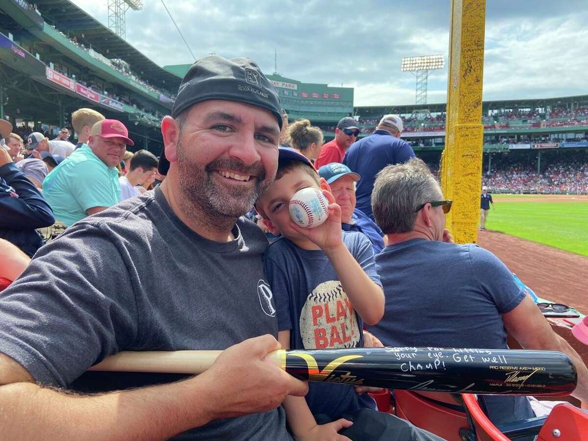 Brian Rascona and his son Luca, 5, hold up a bat signed and delivered by Oakland Athletics right fielder Ramón Laureano during a June 16, 2022, game at Fenway Park.