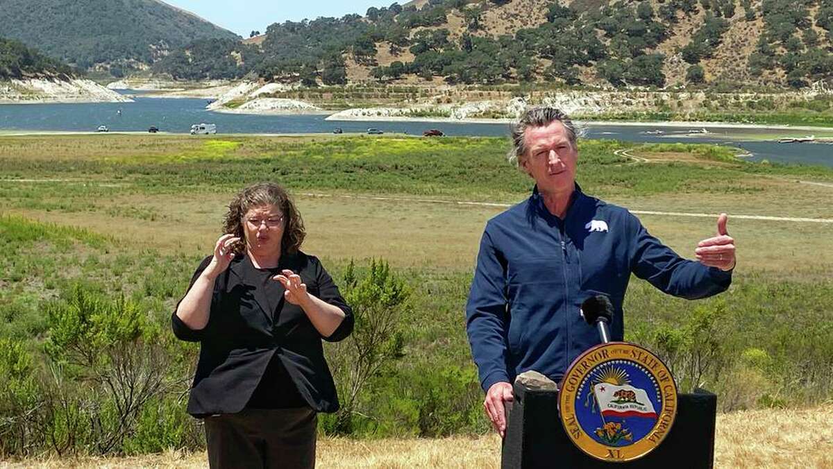 Gov. Gavin Newsom has refused to follow in former Gov. Jerry Brown’s footsteps and mandate that all residents cut back on water use amid the worsening California drought. But Newsom’s calls for voluntary conservation aren’t working. Newsom and sign interpreter Julia Townsend stand at the edge of a diminished Lopez Lake near Arroyo Grande (San Luis Obispo) in July 2021.
