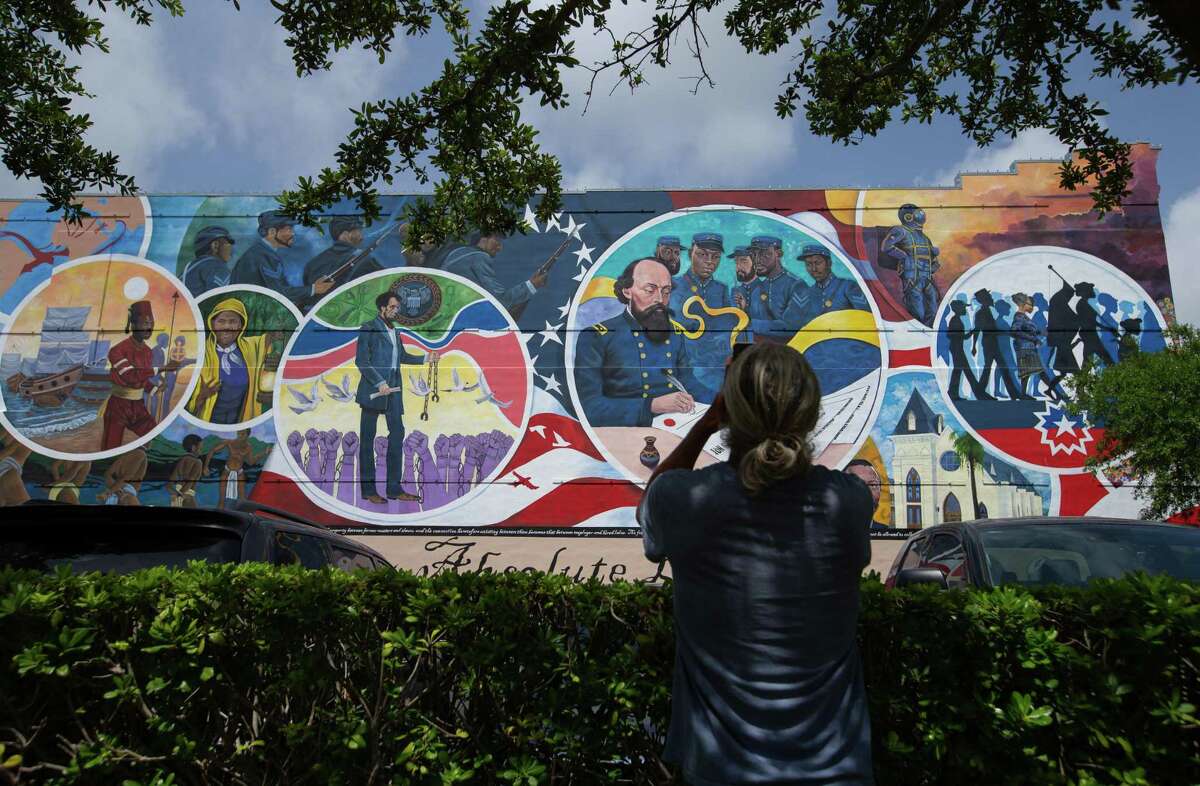 A visitor takes a cellphone photograph of the Absolute Equality Mural, which was unveiled last year for Juneteenth, on Wednesday, June 15, 2022, in Galveston, the birthplace of Juneteenth. The city has seen a steady decline in its Black population.