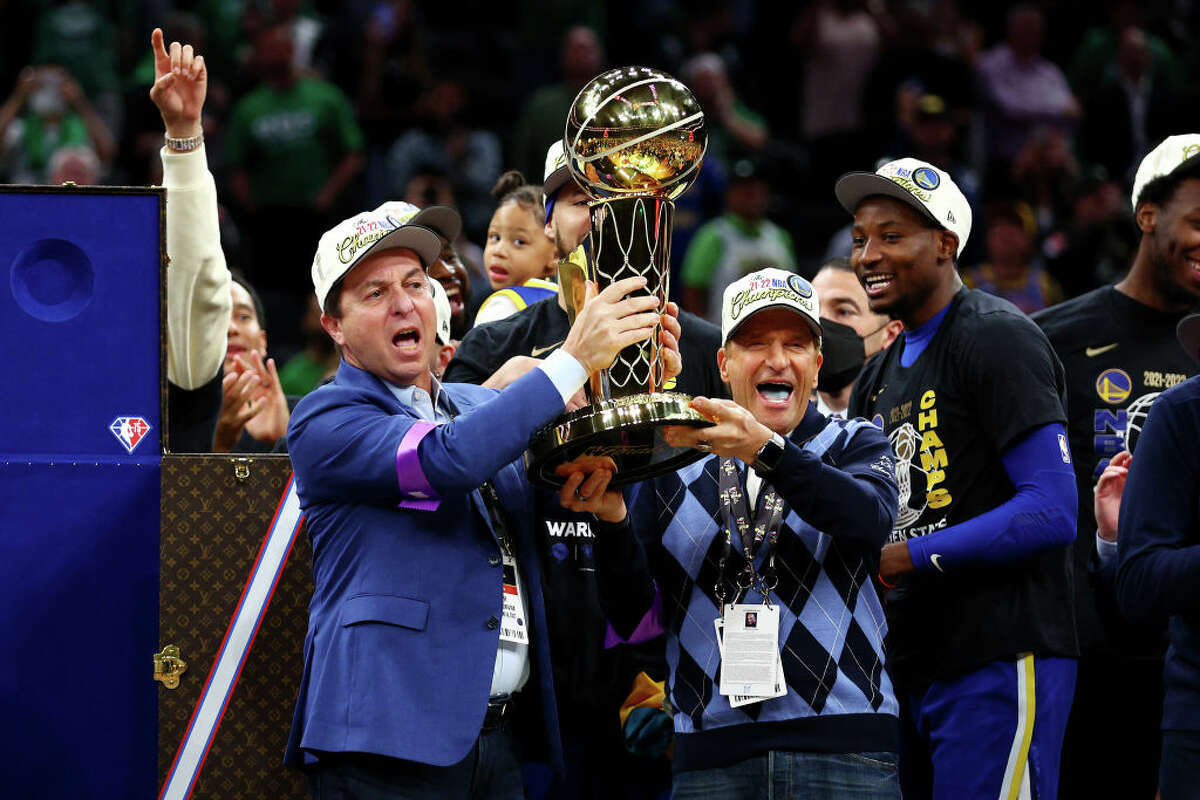 Owners Joe Lacob and Peter Guber of the Golden State Warriors raise the Larry O'Brien Championship Trophy after defeating the Boston Celtics 103-90 in Game Six of the 2022 NBA Finals at TD Garden on June 16, 2022 in Boston.