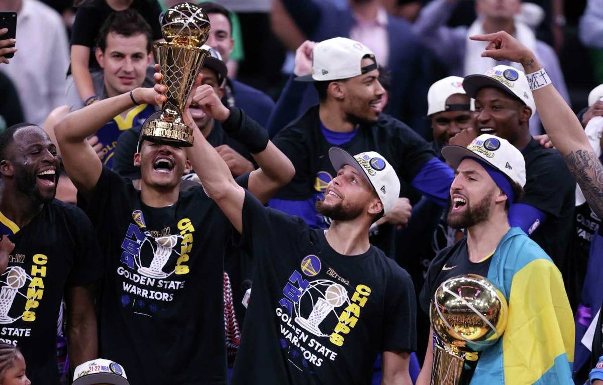 Golden State Warriors’ Stephen Curry holds the MVP trophy as Klay Thompson holds the Larry O’Brien Trophy after Warriors won NBA Championship with a 103-90 win over Boston Celtics in Game 6 of NBA Finals at TD Garden in Boston Mass., on Thursday, June 16, 2022.