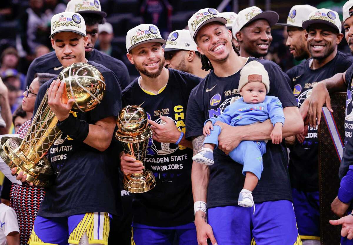 Golden State Warriors' Jordan Poole, 3, holds the Larry O’Brien Championship Trophy and Stephen Curry, 30, holds the Bill Russell NBA Finals Most Valuable Player Award after the Golden State Warriors defeated the Boston Celtics in Game 6 to win the NBA Finals at TD Garden in Boston, Mass., on Thursday, June 16, 2022.