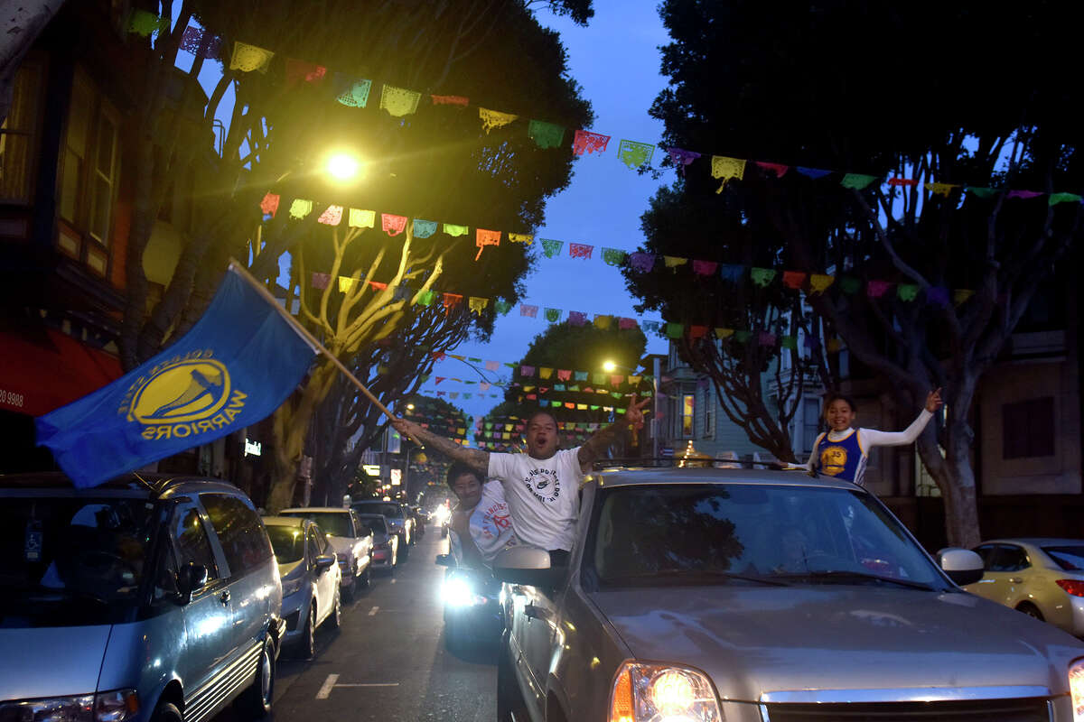 Fans celebrate in a long procession of cars down 24th Street in the Mission District, shortly after the Warriors' victory in the NBA finals, on Thursday June 16, 2022.