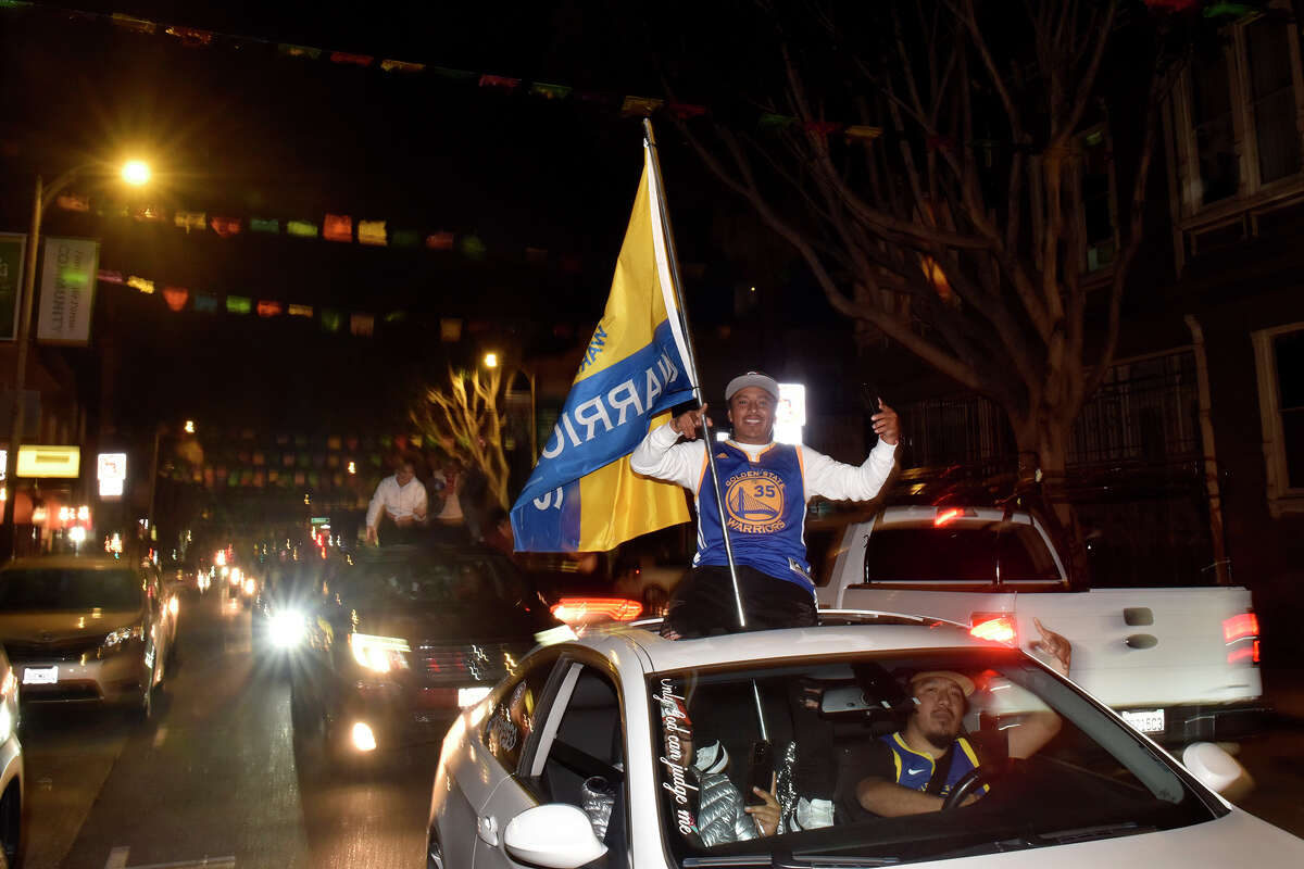Fans celebrate in a long procession of cars down 24th Street in the Mission District, shortly after the Warriors' victory in the NBA finals, on Thursday June 16, 2022.