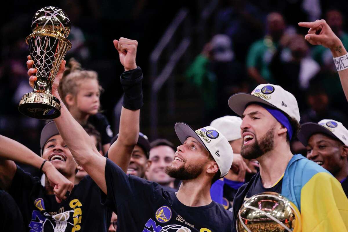 Golden State Warriors' Stephen Curry, 30, holds up the Bill Russell NBA Finals Most Valuable Player Award and Klay Thompson, 11, holds the Larry O’Brien Championship Trophy after defeating the Boston Celtics 103 to 90 in Game 6 of the NBA Finals at TD Garden in Boston, Mass., on Thursday, June 16, 2022.