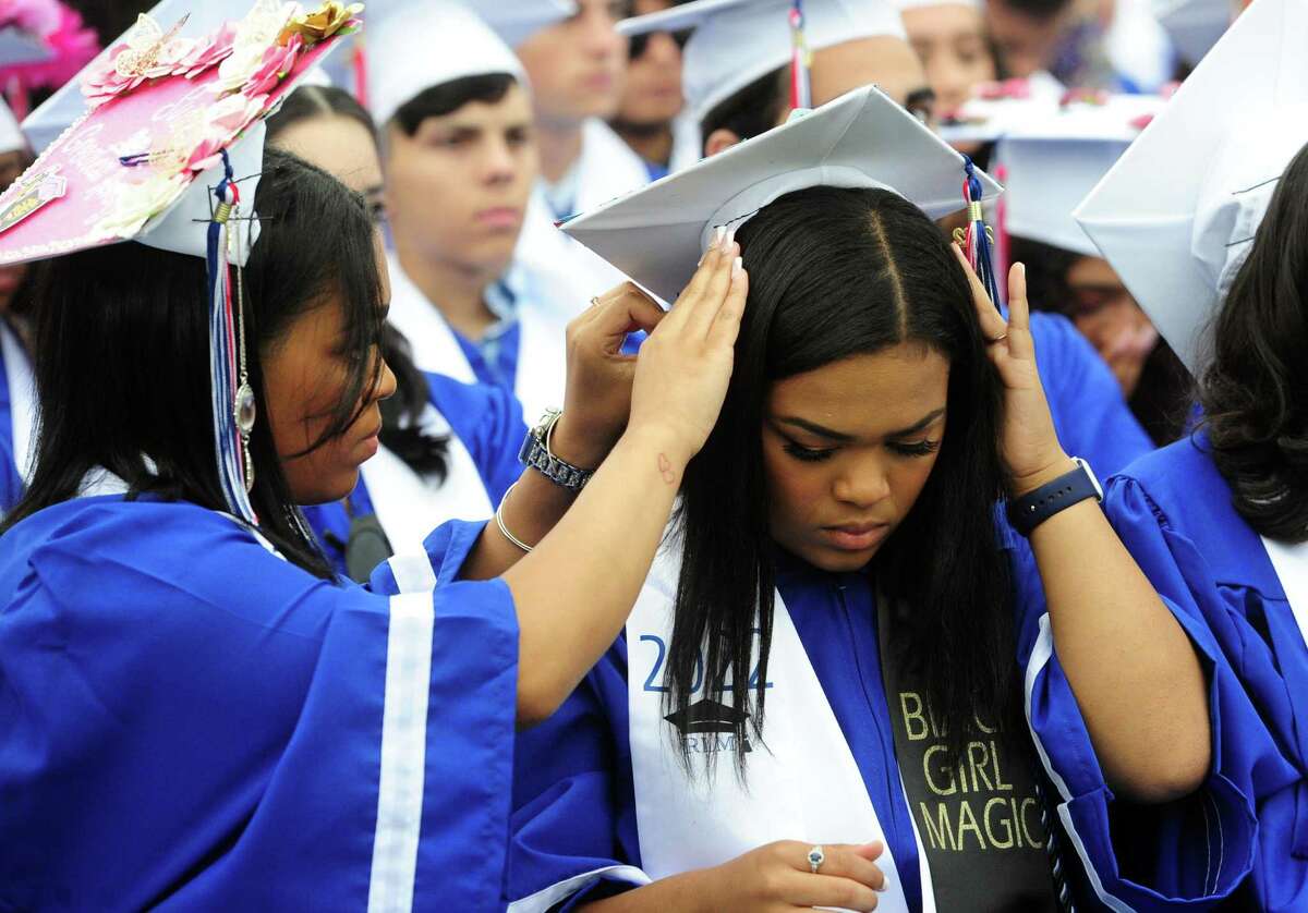 Josie Marshall, left, helps her twin sister Rosie with her graduation cap during Brien McMahon High School's 61st Commencement Exercises in Norwalk, Conn., on Thursday June 16, 2022.