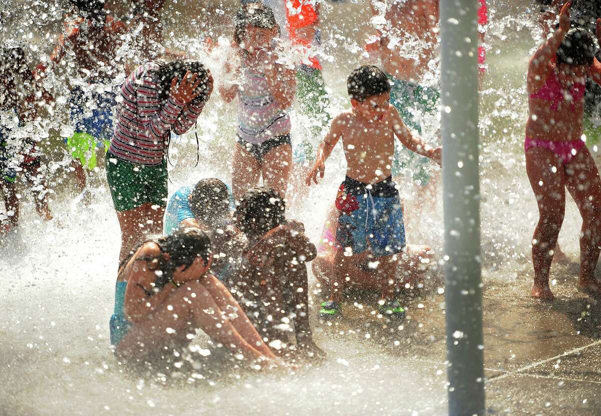 Children are doused in falling water at a Milford splash pad. T