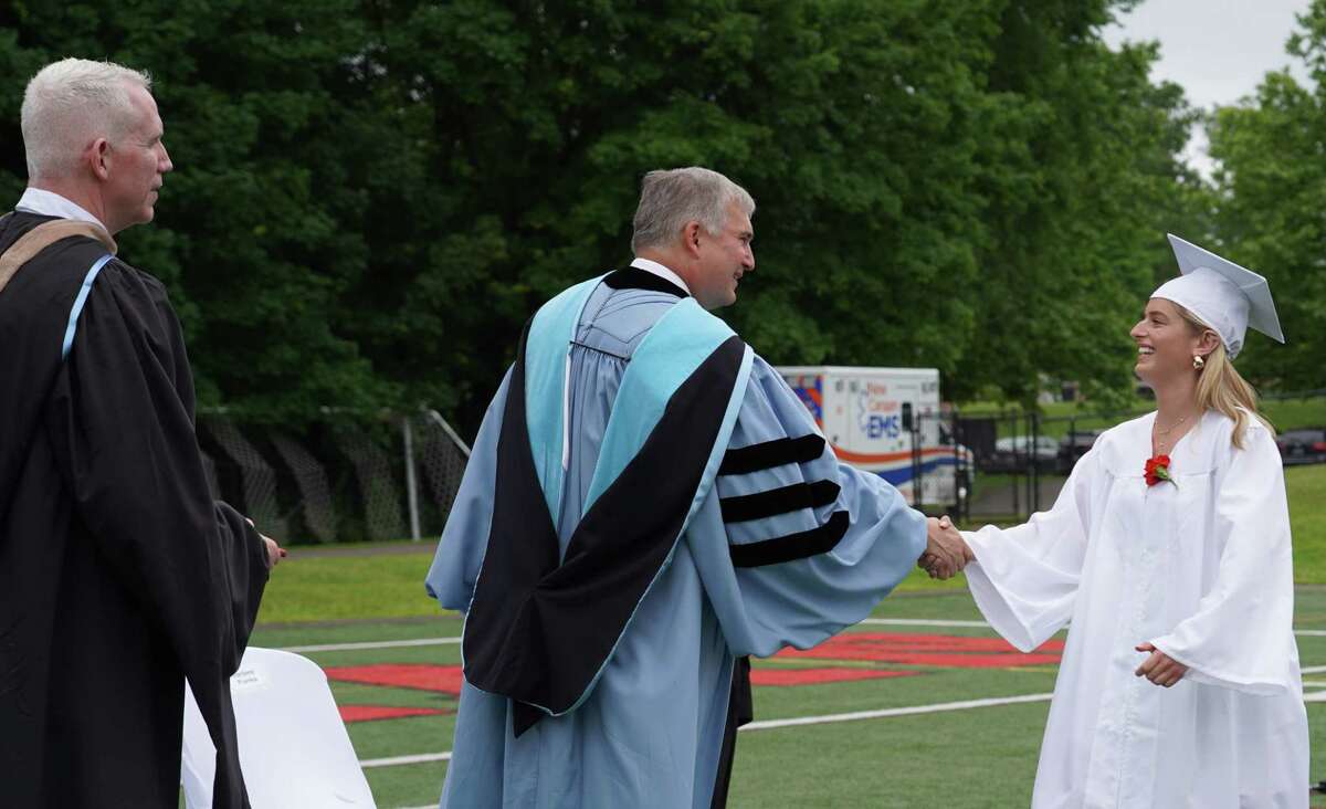 Principal William Egan looked on as Superintendent Bryan Luizzi greets Jacqueline Daniella Siegel as she walks up to get her diploma from New Canaan High School, June 16, 2022.