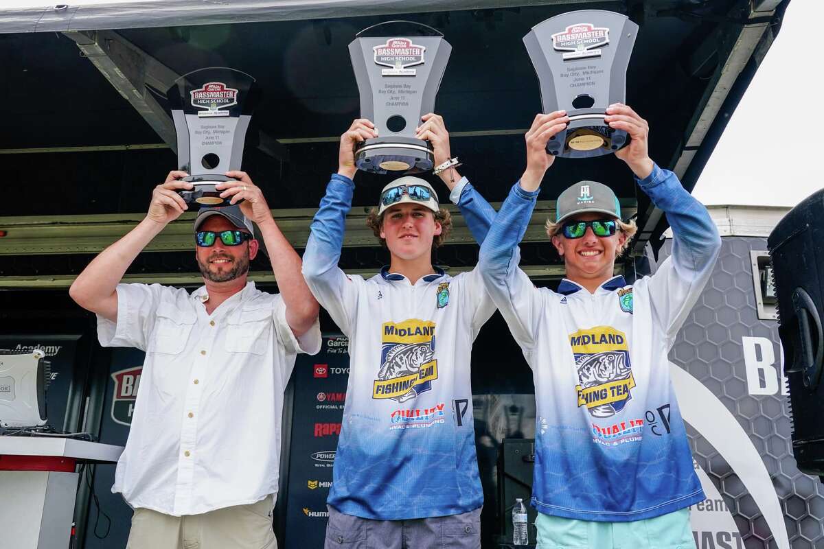 Midland High's Brady Pinwar (right) and Alec Albrecht (center) and coach Amos Mallek pose with their trophies after winning a second straight Bassmaster High School Series national championship on Saginaw Bay last Saturday, June 11, 2022.