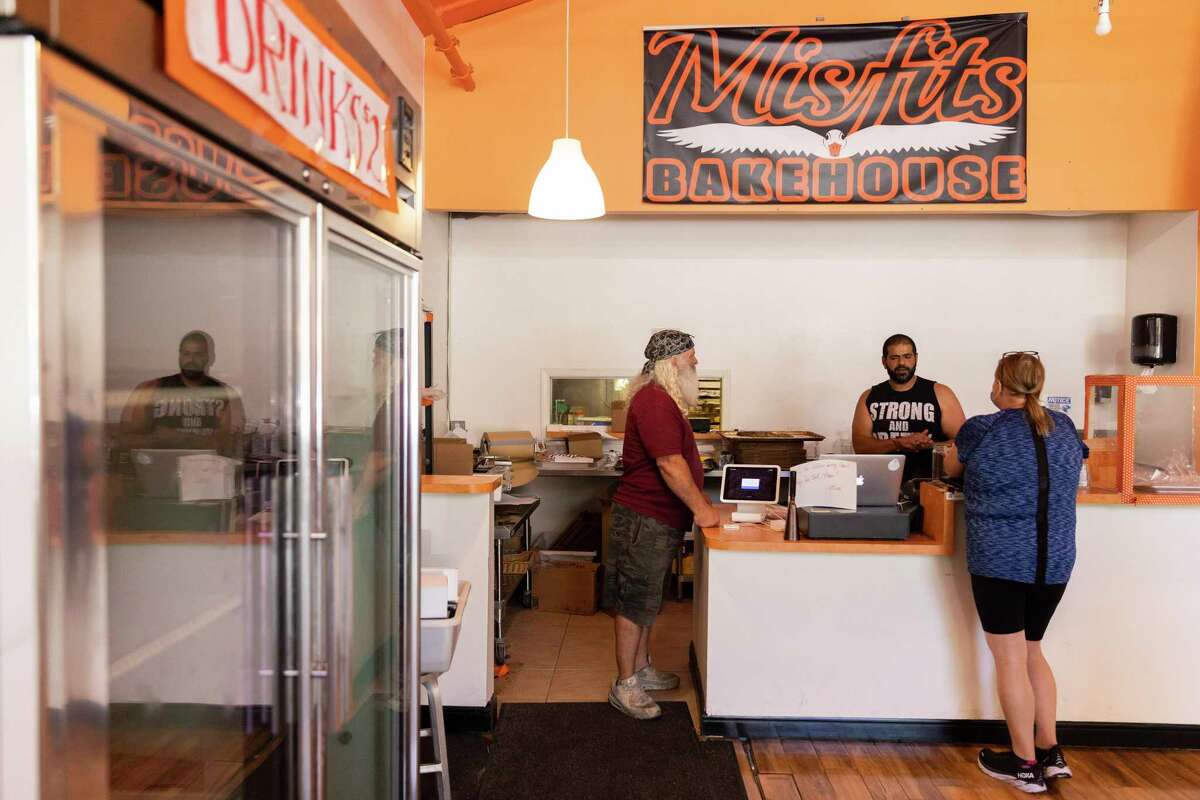 Misfits Bakehouse的老板Mina Makram站在柜台后面帮助一位顾客。周二晚上，这家帕洛阿尔托面包店停电。