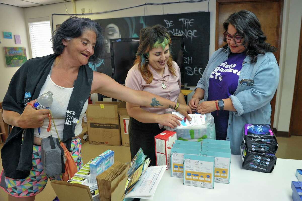 Michelle Rivera (center) and Valerie Jasso Gorospe (right) of ACT for Women and Girls pack reproductive health supplies and information for Natalie Spydell, 43, who is homeless in Visalia (Tulare County). Staff and volunteers prepare these free kits for clients who request them in a part of the Central Valley that is known as an “access desert” for reproductive health care.