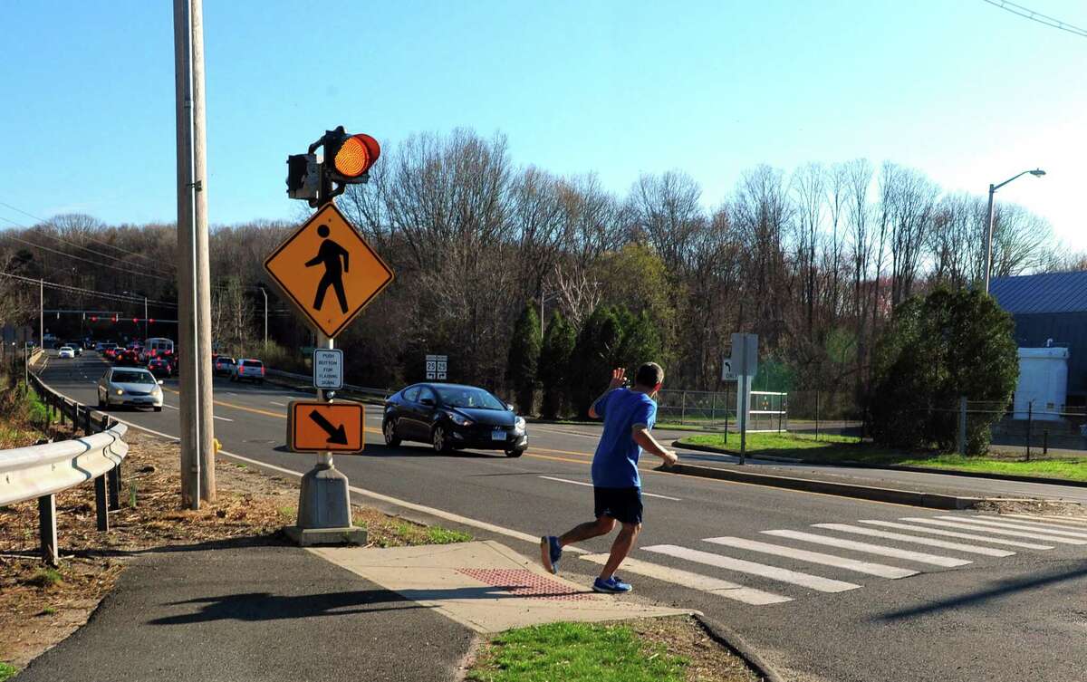 A pedestrian waves to a motorist as he crosses Route 111 at Old Mine Park in Trumbull, Conn., on Tuesday Apr. 18, 2017. Bikers and pedestrians have to use extreme caution when crossing the busy road to connect with the trail on the other side.