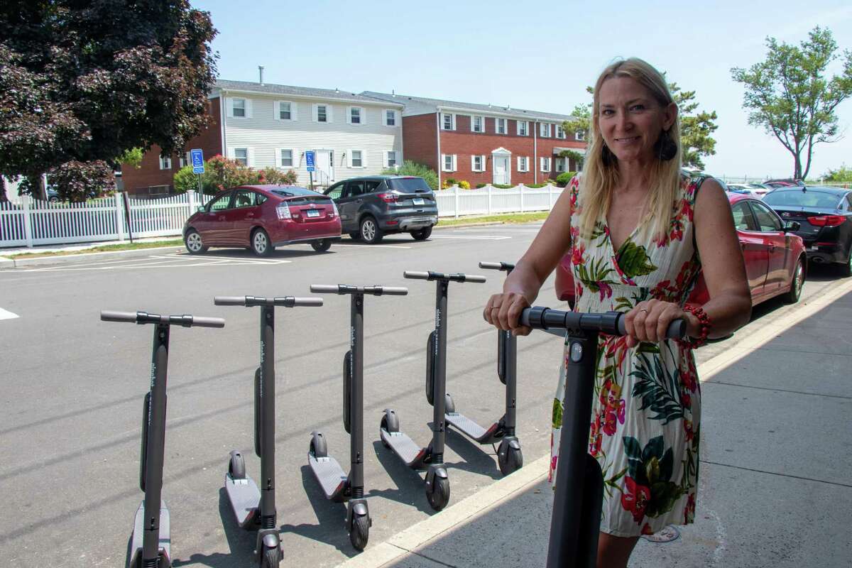 Tina Pritchard stands on one of the new commuter scooters available to rent at her business, Scoot and Paddle.
