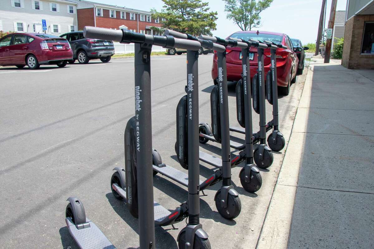 Tina Pritchard stands on one of the new commuter scooters available to rent at her business, Scoot and Paddle.