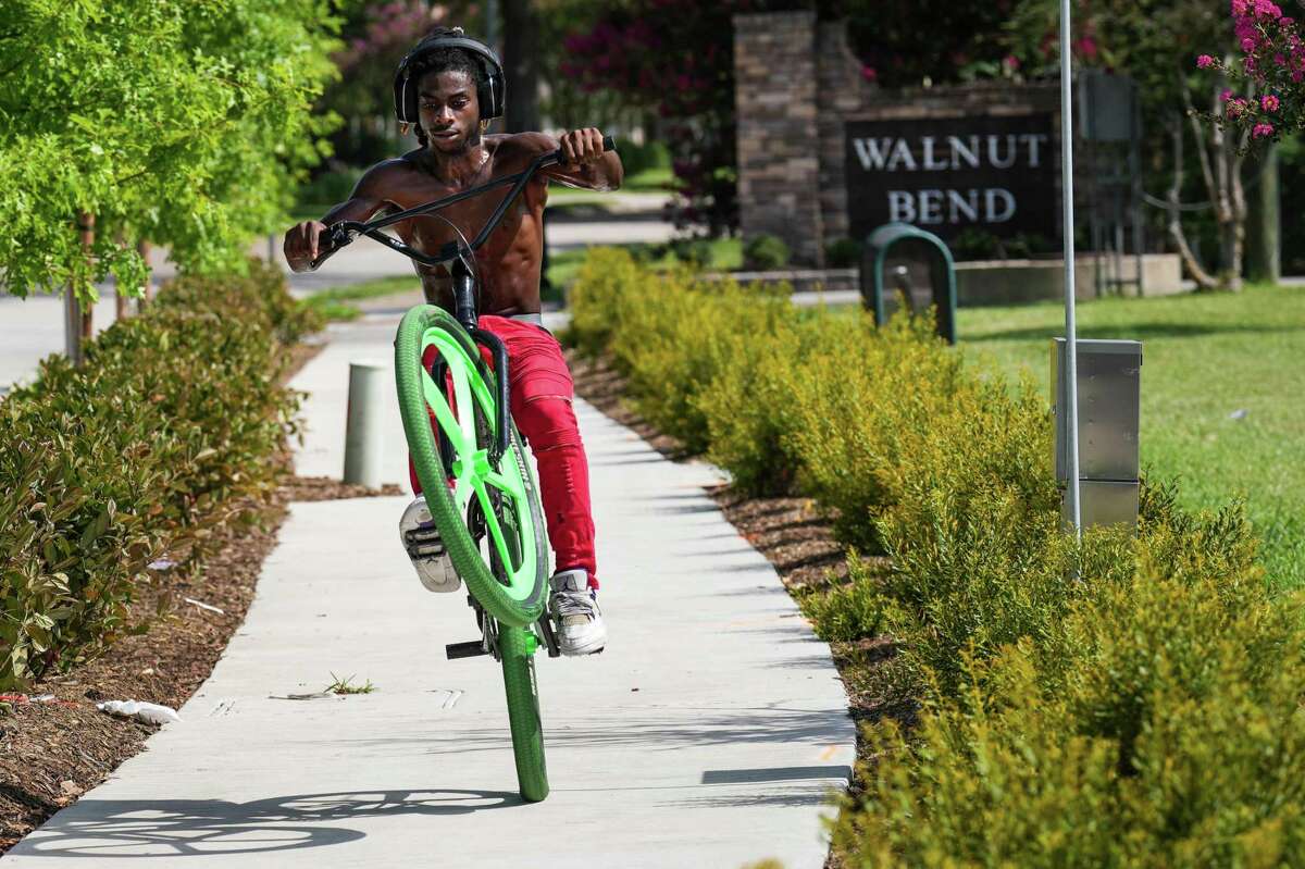 Jamir Barnett, 19, rides his bike along Walnut Bend where workers have added many new features and landscaping in Westchase District Friday, June 17, 2022 in Houston. Using local and state funds, Westchase Management District spent $20 million rebuilding just more than one mile of Walnut Bend from Westheimer to Westpark Drive, improving drainage, replacing the automobile lanes and widening sidewalks to landscape and enhance bus shelters.