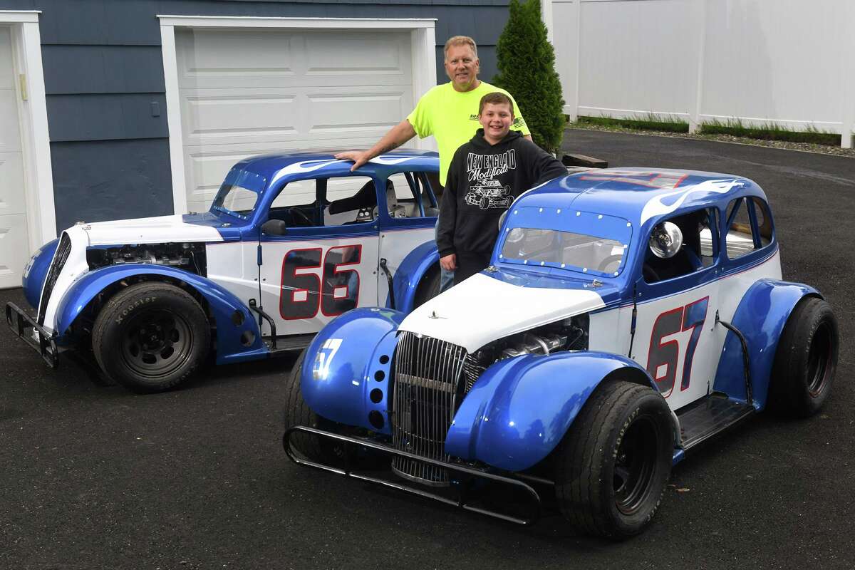 Ron Miske and his son, Tyler, 12, pose next to their Legend series race cars in front of their home in Shelton, Conn. May 19, 2022.