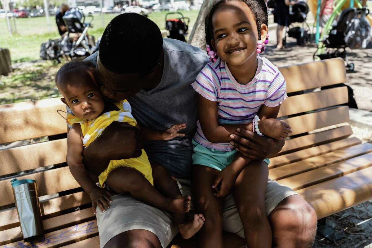 在奥克兰举行的第二次海湾黑人爸爸聚会上，奥巴塔拉·马乌西抱着他的女儿们在阿斯特罗公园。