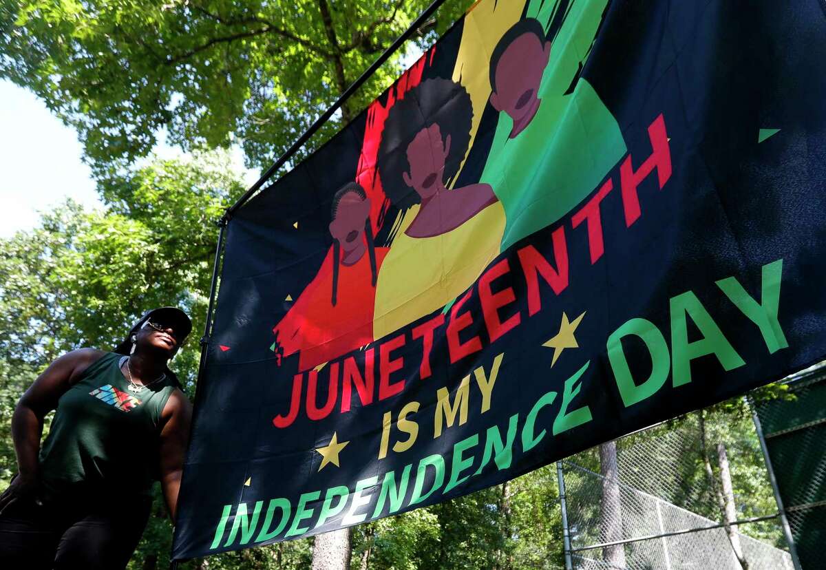 A woman hangs a Juneteenth flag last year in Conroe. Long before Juneteenth would be recognized as a federal holiday, it was a day to recognize independence, Thanksgiving, family, new opportunities and much more.