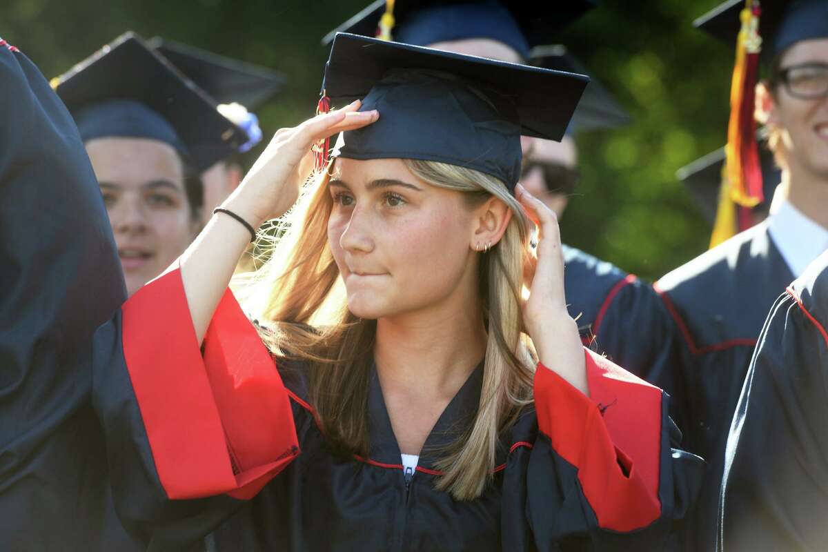 Layla Carlberg adjusts her cap against the wind at the beginning of the graduation ceremony Friday.