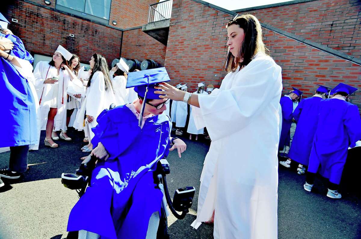 Shea Dolce, right, assists classmate Tripp Lyons with his graduation cap before the start of Darien High School's Class of 2022 Commencement Program in Darien, Conn., on Friday June 17, 2022.