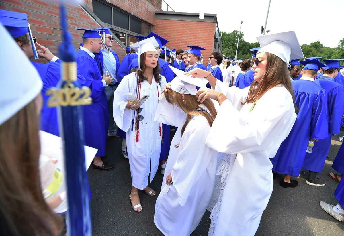 Kelly Dolce, right, assists classmate London Sinclair with her graduation cap before the start of Darien High School's Class of 2022 Commencement Program in Darien, Conn., on Friday June 17, 2022.