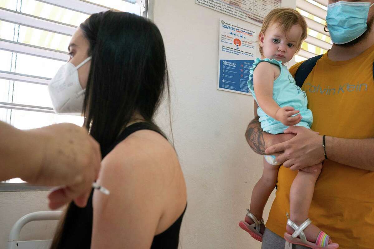 Diana Hernandez, 24, left, gets a follow-up vaccination at a clinic in Playa, the northernmost municipality in Havana, alongside her daughter, Manuelita Sarracino, 15 months, and husband, Juan P. Sarracino, 25, look on.