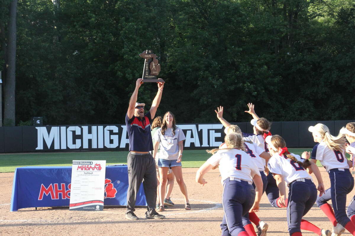 USA's Isaiah Gainforth lifts the state championship trophy, and the players celebrate. He steps down as head softball coach after five seasons.