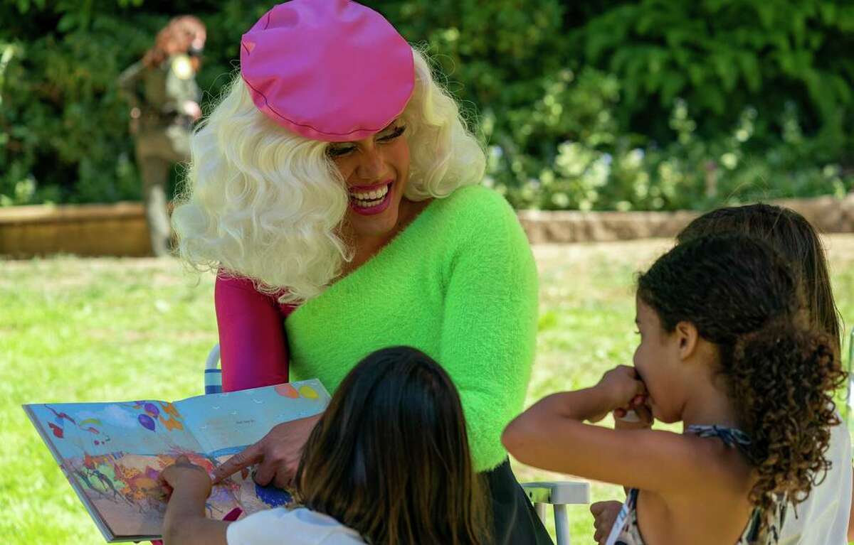 在旧金山金门公园举行的“变装皇后故事时间”活动中，伊夫·圣·克罗伊桑特一边给孩子们朗读，一边指出角色。