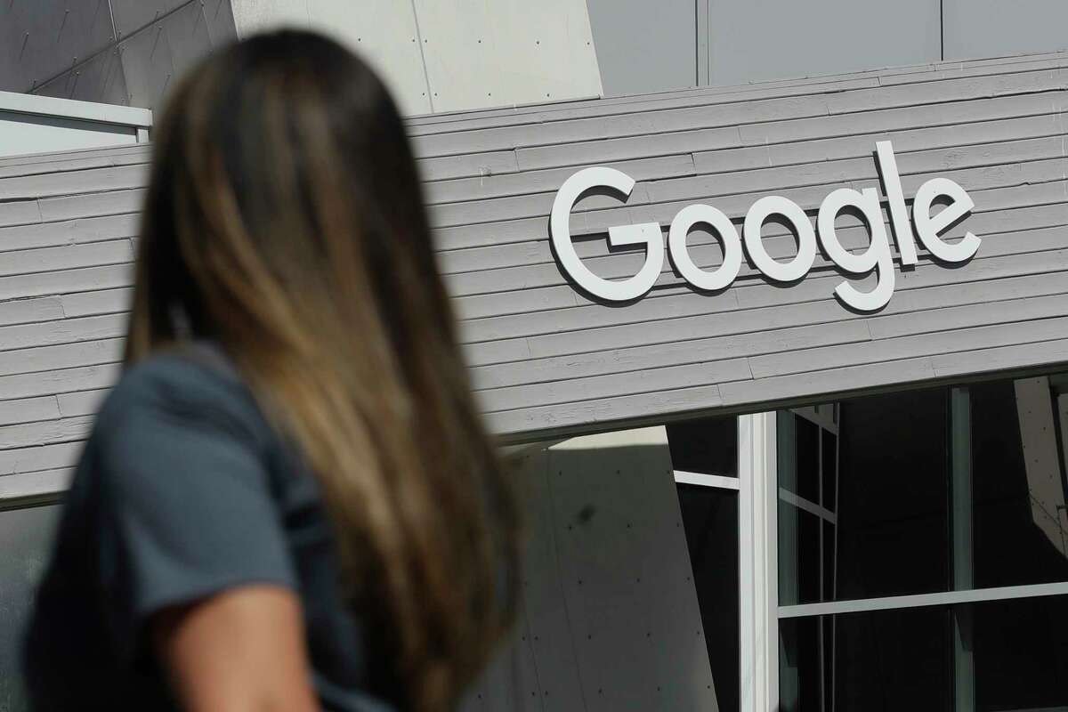 FILE - In this Sept. 24, 2019, file photo a woman walks below a Google sign on the campus in Mountain View, Calif. In January, a group of Google engineers and other workers announced they had formed a union, a rare foothold for the labor movement in the tech industry. The group formed the Alphabet Workers Union last year, which represents around 800 Google employees and is run by five people who are under 35. Alphabet is Google's parent company.